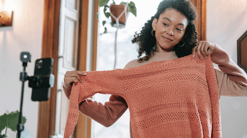 Photo of a woman trying on a sweater illustrating the theme of the article about marketing tips for the fashion industry.