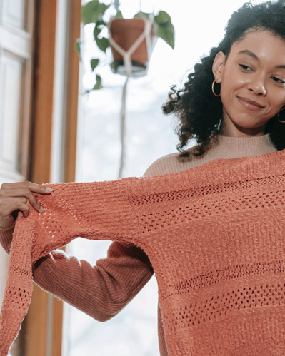 Photo of a woman trying on a sweater illustrating the theme of the article about marketing tips for the fashion industry.