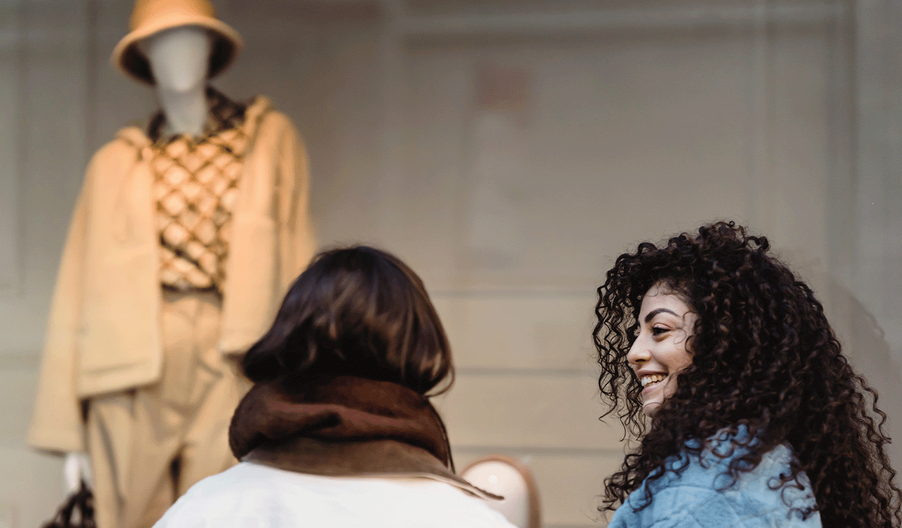 Photo of two women talking and a mannequin in front