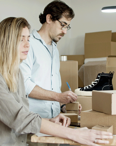 Photo of a woman and a man surrounded by shoeboxes