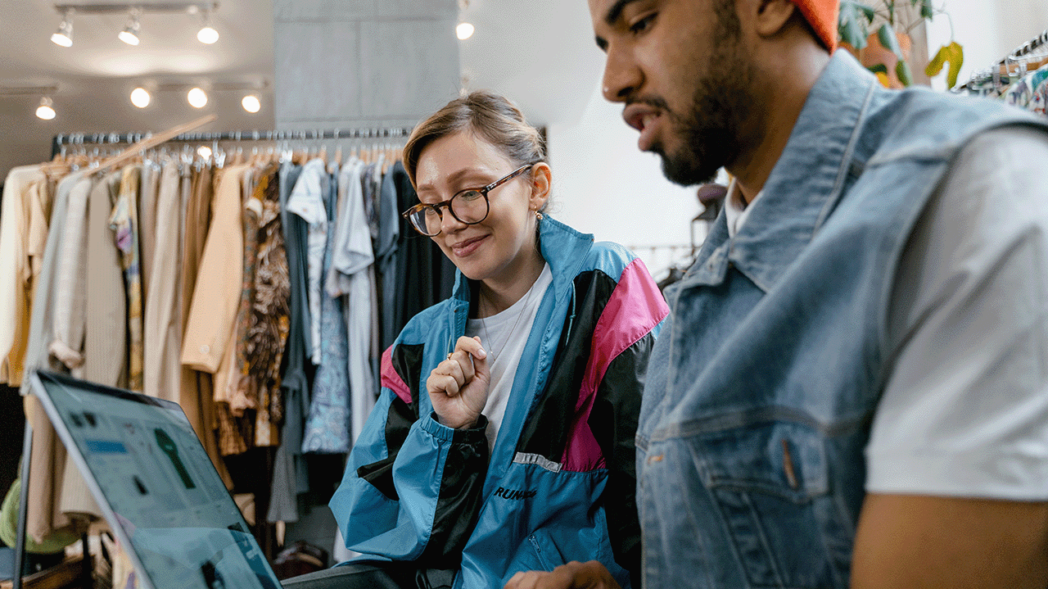 Photo of a woman and a man in a clothing store talking in front of a computer