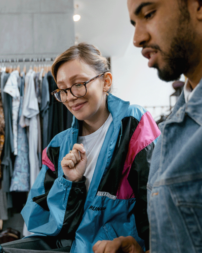 Photo of a woman and a man in a clothing store talking in front of a computer